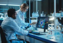 Female Research Scientist with Bioengineer Working on a Personal Computer with Screen Showing Virus Analysis Software User Interface. Scientists Developing Vaccine, Drugs and Antibiotics in Laboratory
